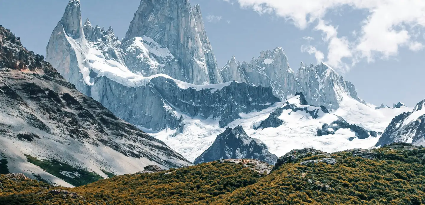 Cordilheira nevada do Fitz Roy sobre encostas de vegetação dourada, na Patagônia.
