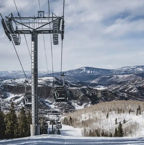 Teleférico sobre a pista de esqui, com as Montanhas Rochosas ao fundo, em Aspen